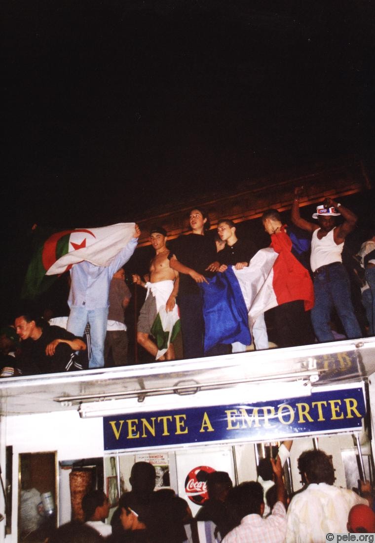 Des fêtards sur le toît de la camionette d'un vendeur ambulant, drapeau Algérie